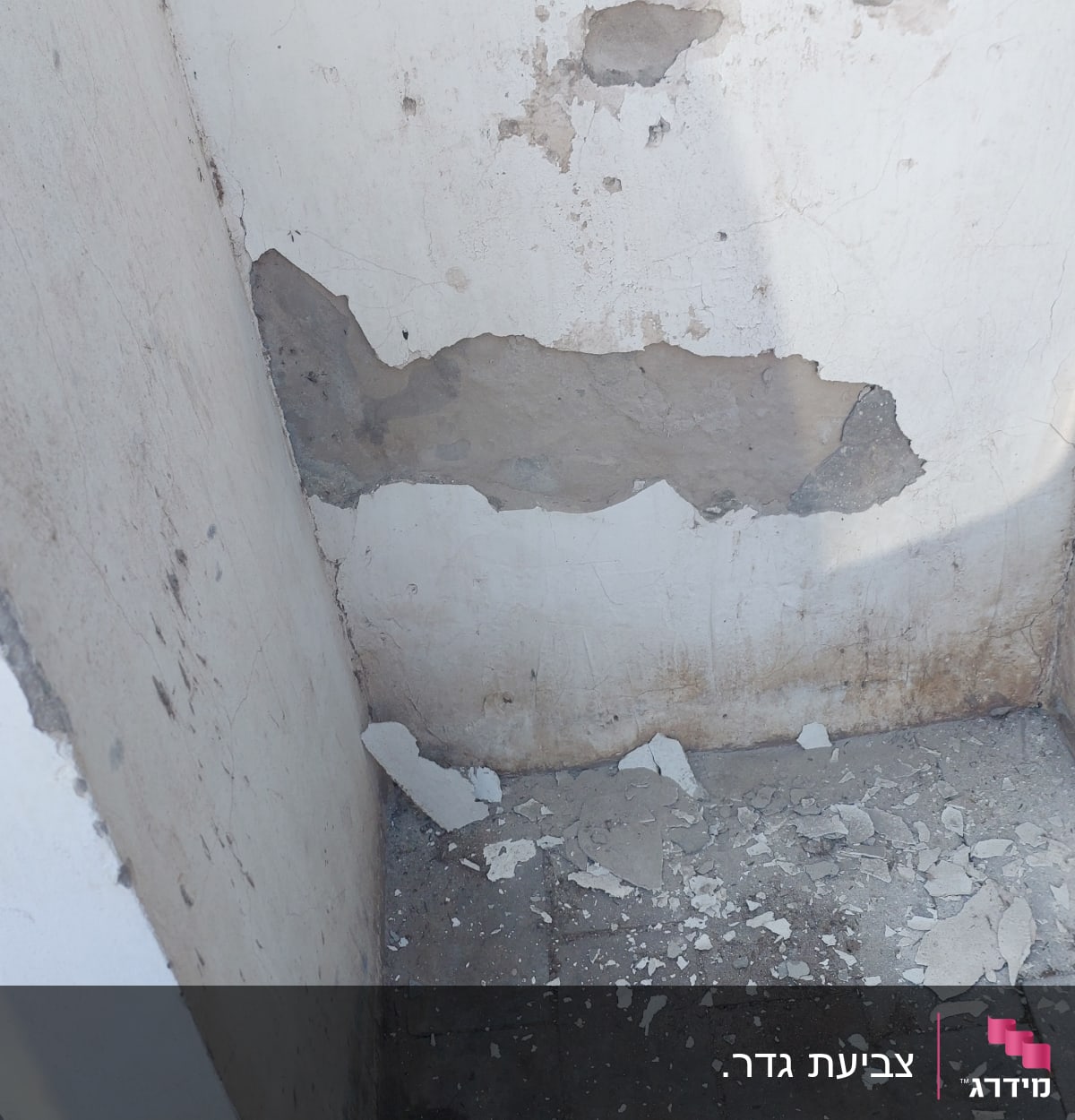 קיר מתקלף עם טיח מתפורר על הרצפה